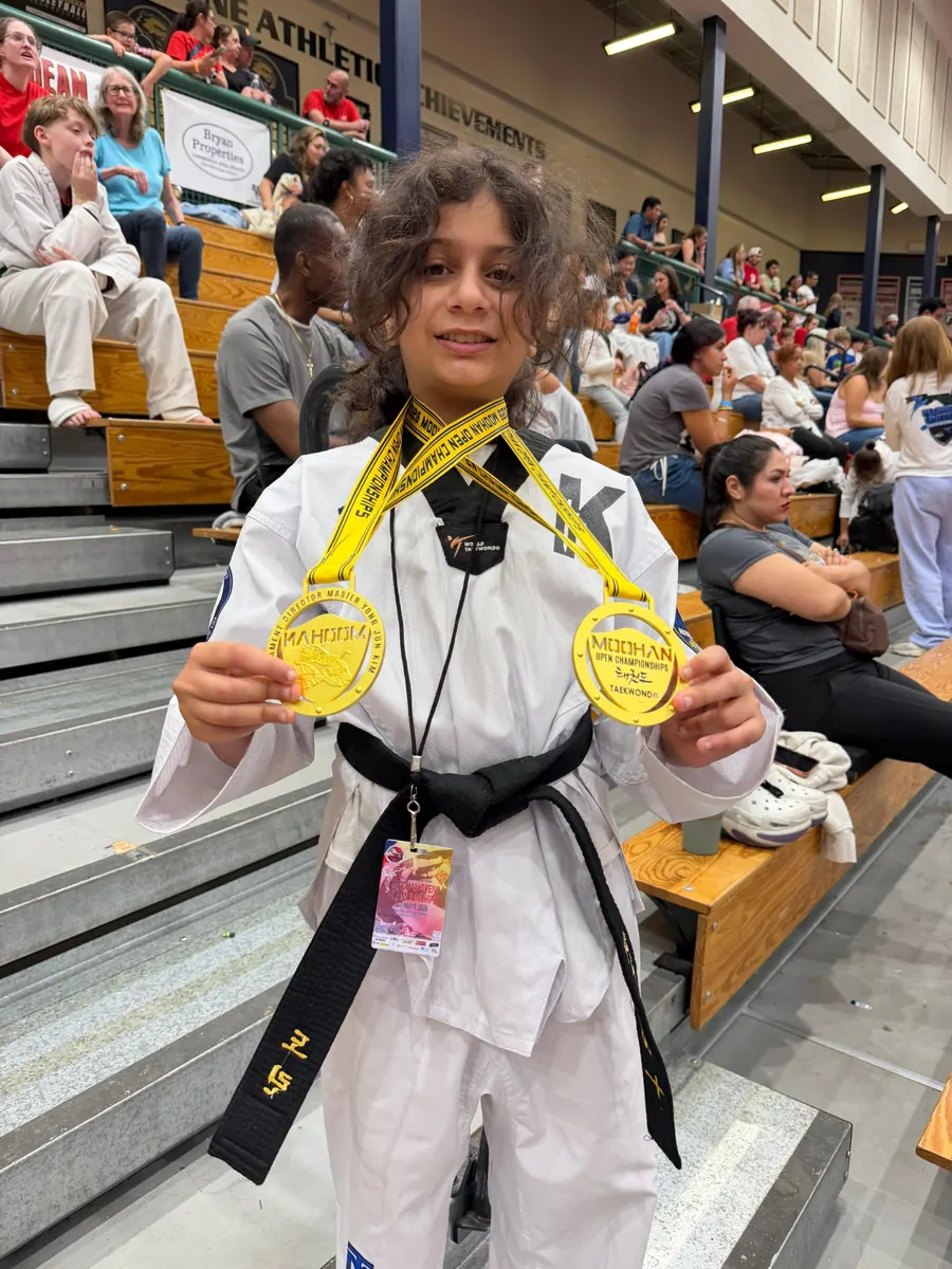 Black belt competitor proudly displaying two championship medals