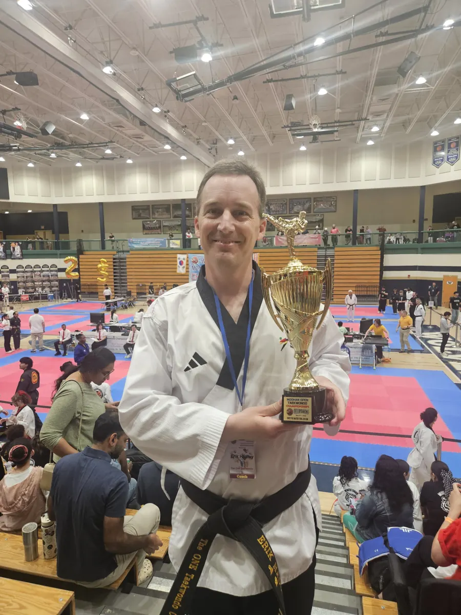Instructor celebrating a championship trophy in the tournament gym