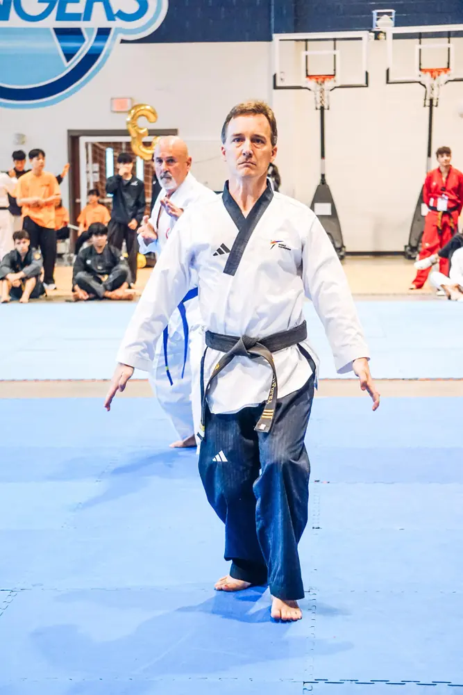 Black belt master demonstrating a form on the competition mat